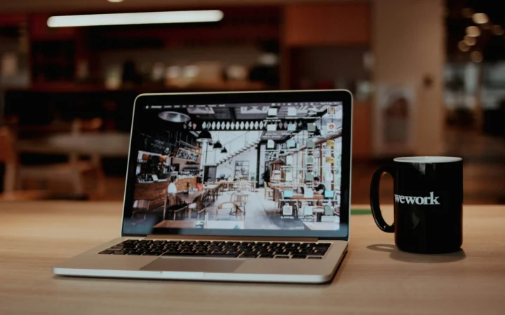 Laptop i kubek kawy na biurku — wybór narzędzia AI do pracy w małej firmie